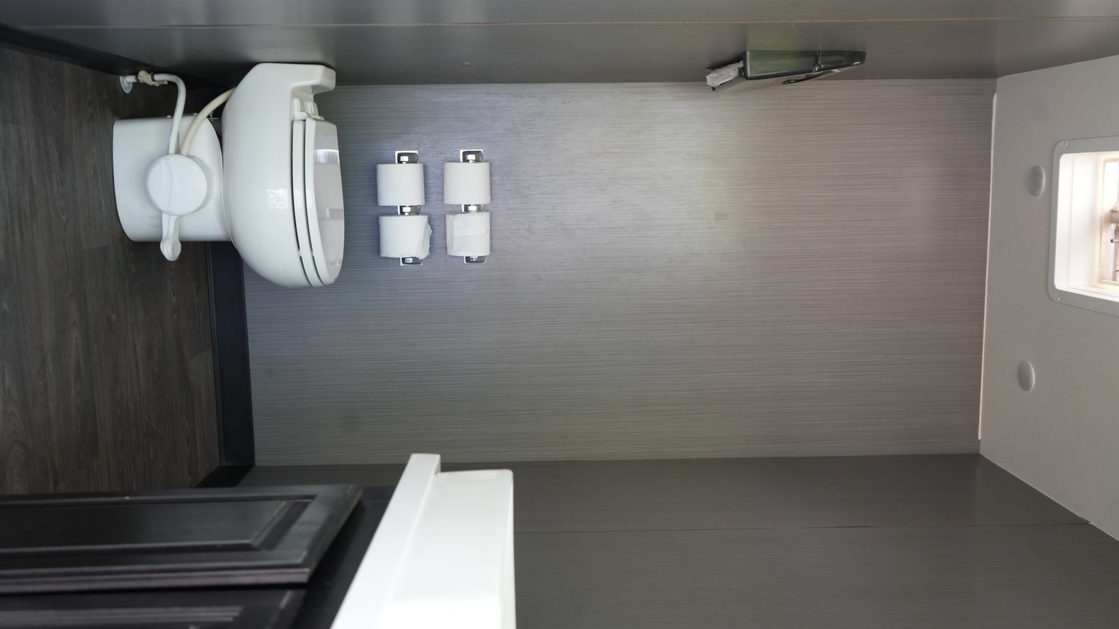 Luxury restroom stall interior with porcelain toilet and hardwood floors